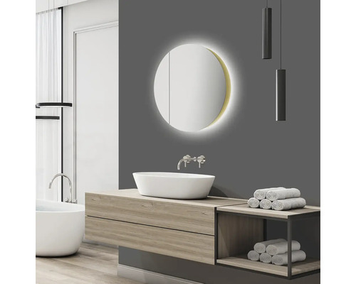 Badezimmer mit Waschtisch, rundem Spiegel mit Beleuchtung und Handtüchern