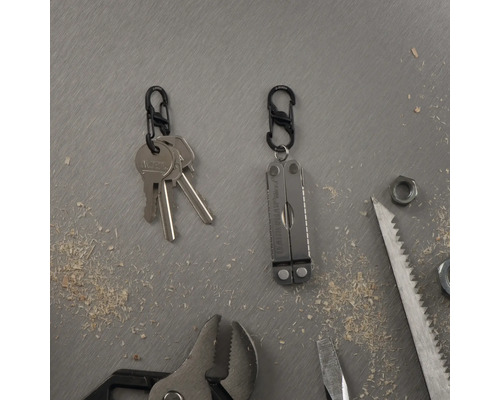 Schlüssel mit Karabiner und Multifunktionswerkzeug neben Werkzeugen auf Werkbank