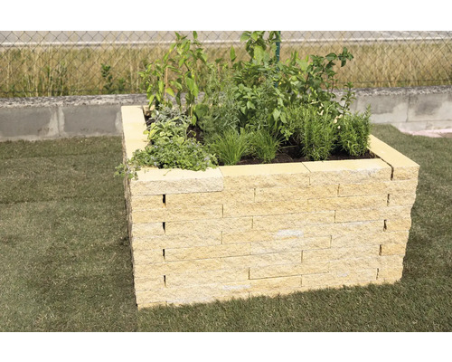 Hochbeet aus Stein mit Pflanzen auf Rasen