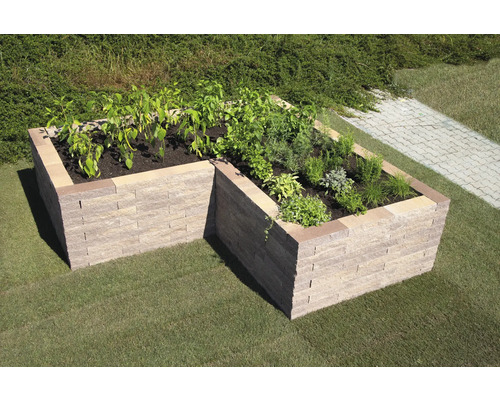 Hochbeet aus Steinblöcken im Garten mit Gemüse und Kräutern bepflanzt