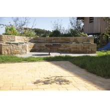 Garten mit Steinmauer, Sitzgelegenheiten mit Kissen und Feuerstelle