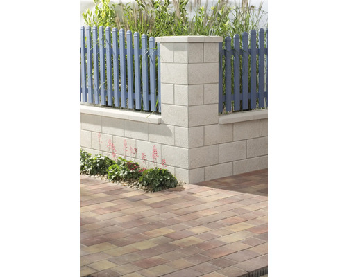 Detailansicht eines Gartens mit Betonmauer, Holzzaun und Pflastersteinen