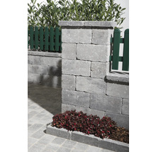 Detailansicht einer Gartenmauer aus Betonsteinen mit Zaunelementen und Bepflanzung.