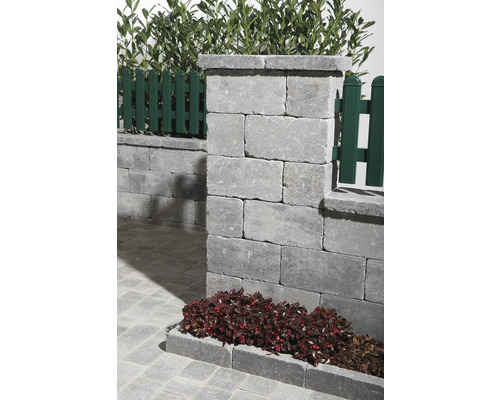 Detailansicht einer Gartenmauer aus Betonsteinen mit Zaunelementen und Bepflanzung.