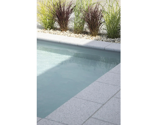 Pool mit Wasseroberfläche, umgeben von Kies und dekorativem Gras