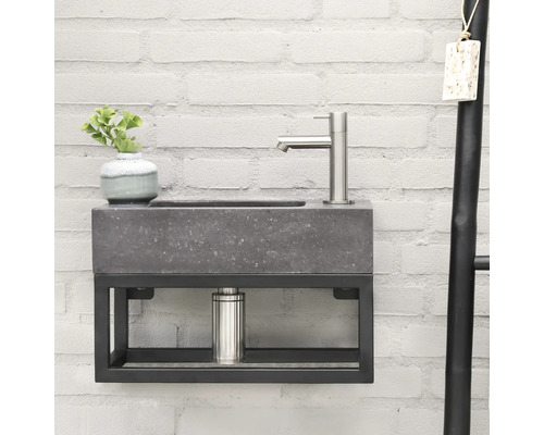 Waschtisch mit Betonbecken und Metallgestell an einer Ziegelwand