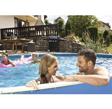 Familie entspannt im Aufstellpool im Garten mit Grill und Gartenmöbeln