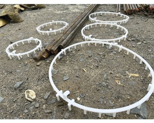 Mehrere Abstandshalter aus Kunststoff für Bewehrungskörbe liegen auf dem Boden.