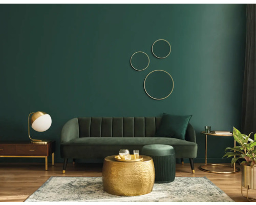 Wohnzimmer mit Sofa, Couchtisch, Teppich und Dekoration vor einer grünen Wand