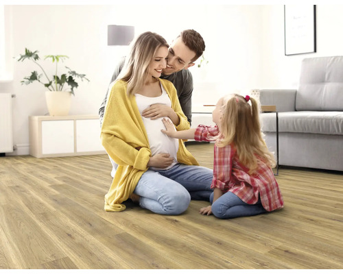 Familie mit Kind auf einem hellen Holzboden im Wohnzimmer.