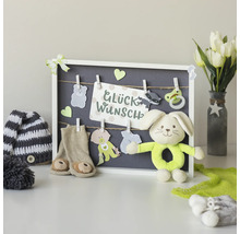 Dekoratives Arrangement mit Babyaccessoires, Glückwunschkarte, Stofftier und Tulpen in einer Vase