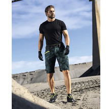 Ein Mann trägt ein schwarzes T-Shirt, Arbeitshandschuhe, eine kurze Arbeitshose mit Tarnmuster und Arbeitsschuhe.