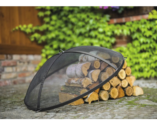 Schwarzer Funkenschutz für Feuerstelle über einem Holzstapel