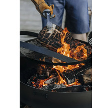Grillgut wird über einem Holzkohlegrill mit einer Zange gewendet