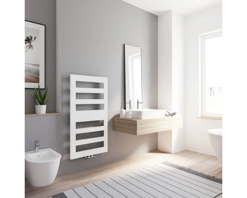 Helles Badezimmer mit weißem Heizkörper, Waschtisch, Spiegel und Bidet.