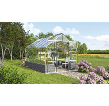 Gewächshaus mit Regalen, Tisch und Stühlen im Garten