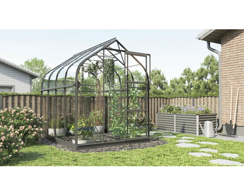 Gewächshaus im Garten mit Hochbeet und Gartenwerkzeugen