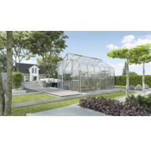 Gewächshaus im Garten mit Bepflanzung und Haus im Hintergrund