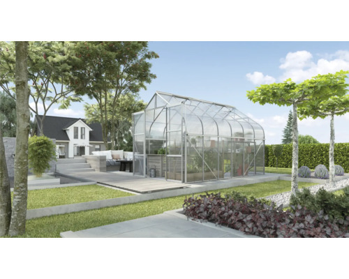 Gewächshaus im Garten mit Bepflanzung und Haus im Hintergrund