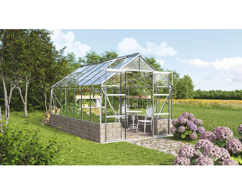 Gewächshaus mit Glaswänden und Steinfundament im Garten