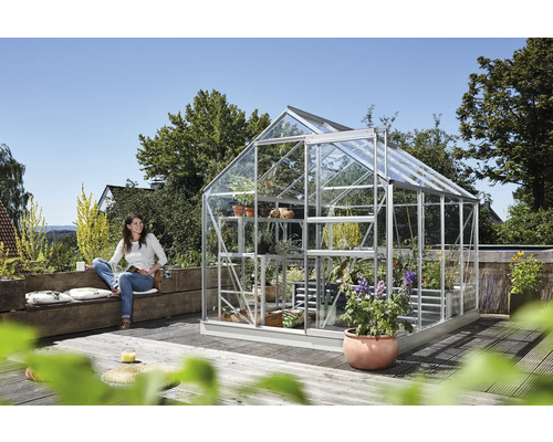 Gewächshaus mit Pflanzen und einer Frau, die auf einer Bank sitzt