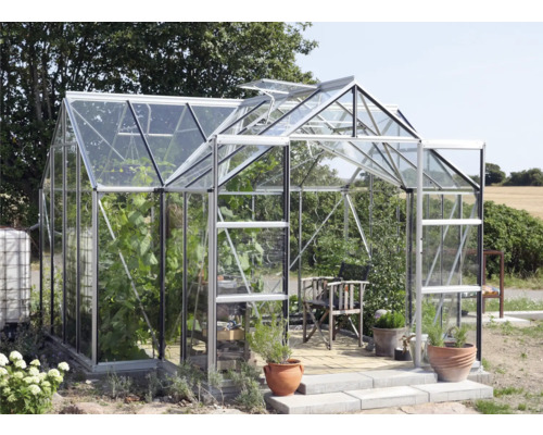 Gewächshaus mit Pflanzen, Stuhl und Töpfen im Garten