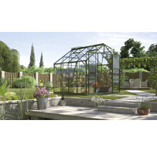 Gewächshaus im Garten mit Pflanzen und Gartenmöbeln auf der Terrasse.