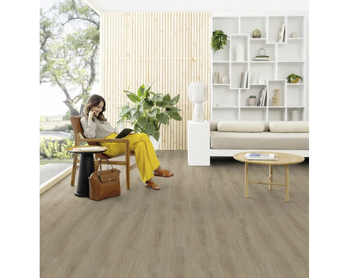 Wohnzimmer mit Holzfußboden und einer Frau, die auf einem Sessel sitzt