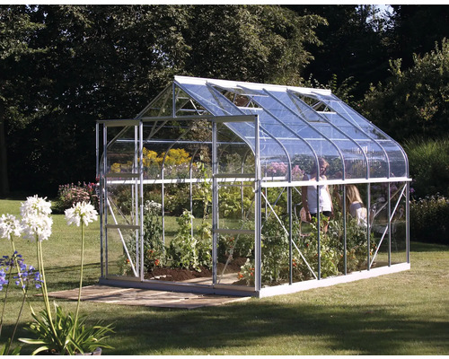 Gewächshaus mit Pflanzen und Garten im Hintergrund