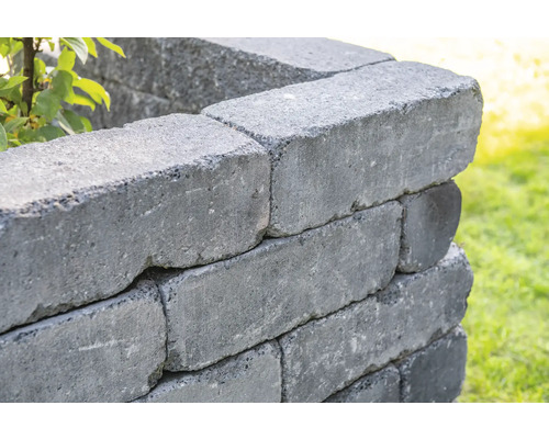 Nahaufnahme einer Mauer aus grauen Betonsteinen im Garten.