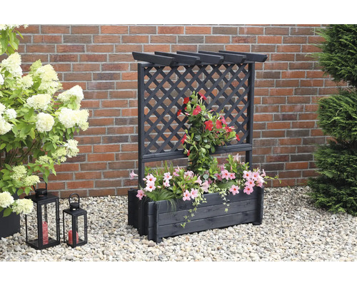 Blumenkasten mit Rankgitter aus Holz mit Blumen und Pflanzen vor einer Ziegelwand