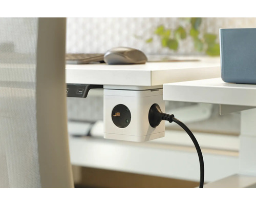 Würfelförmige Steckdosenleiste an einem weißen Schreibtisch mit eingestecktem Stromkabel