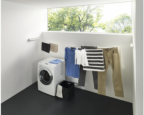 Wäscheständer mit Wäsche, Waschmaschine und Fenster in einem hellen Raum
