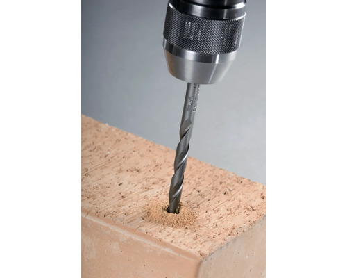 Bohrmaschine bohrt Loch in einen Ziegelstein.