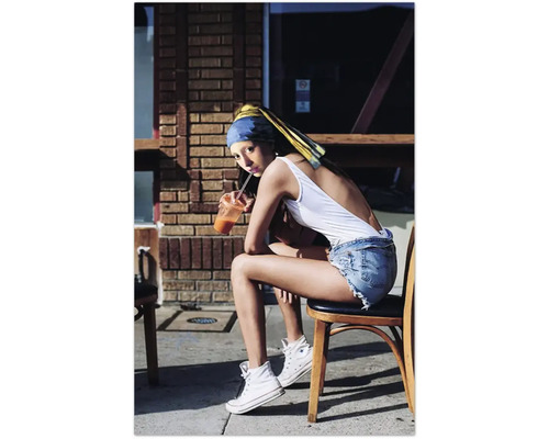 Eine Frau mit einem blauen Stirnband und gelbem Tuch sitzt auf einem Stuhl und trinkt ein Getränk.