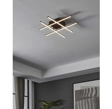 Moderne Deckenleuchte mit sich kreuzenden LED-Leuchtstäben in einem Wohnzimmer.