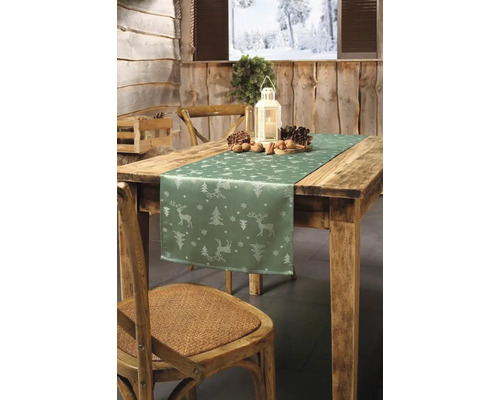 Festlich gedeckter Holztisch mit Tischläufer, Laterne, Tannenzapfen und Nüssen für die Weihnachtszeit.