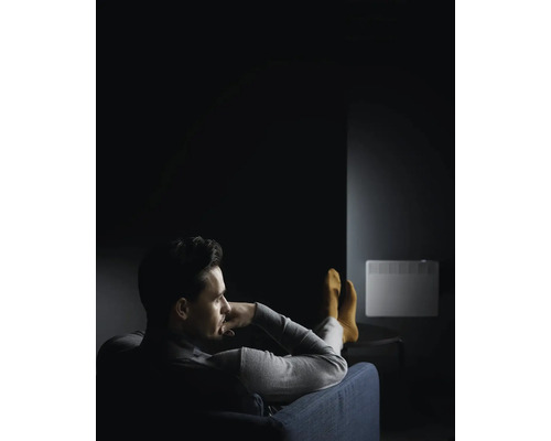 Mann entspannt auf einem Sofa vor einem Heizkörper an der Wand