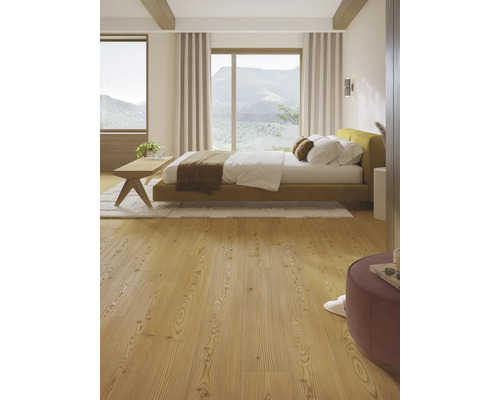 Helles Schlafzimmer mit Bett, Holzfußboden und Ausblick auf die Berge.