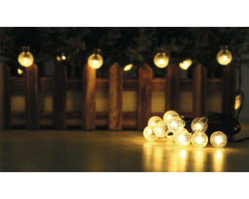 Lichterkette mit runden Lampen und Holzzaun im Hintergrund