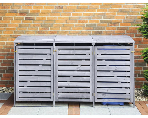 Dreifache Mülltonnenbox aus Holz mit Lamellen und Deckel vor einer Backsteinmauer