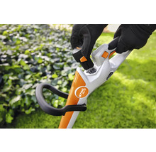 Eine Person setzt einen Akku in einen Akku-Rasentrimmer ein.