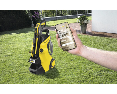 Kärcher Hochdruckreiniger K5 Power Control mit Smartphone in einer Hand auf Rasen
