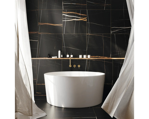 Badezimmer mit freistehender Badewanne vor einer Wand mit Fliesen in Marmoroptik.