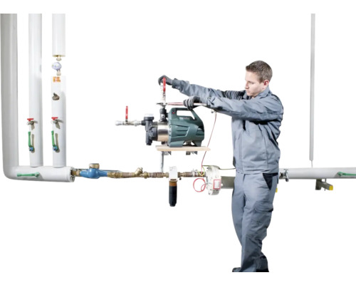 Ein Installateur montiert eine Gartenpumpe an einem Rohrsystem.