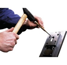 Person schlägt mit Hammer und Durchschlag auf Werkstück