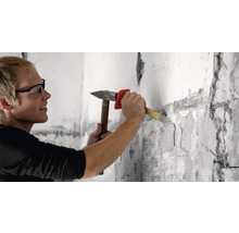 Ein Mann stemmt mit Hammer und Meißel eine Wand auf
