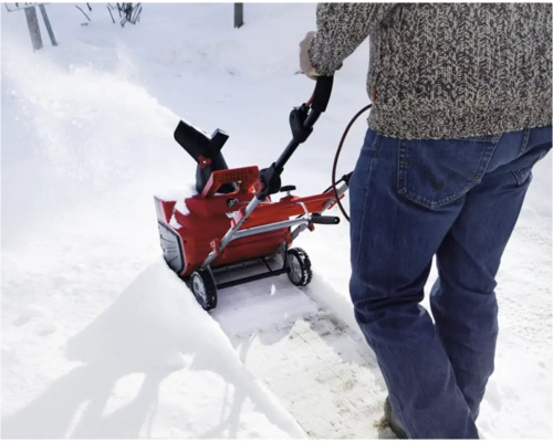 Eine Person benutzt eine Schneefräse, um Schnee zu räumen.