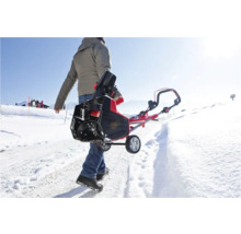 Person trägt eine Schneefräse auf einer schneebedeckten Straße