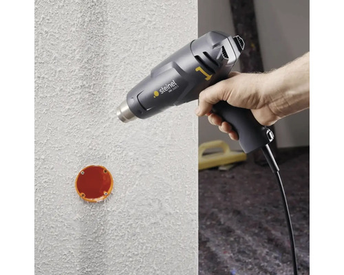 Heißluftpistole in der Anwendung auf einer Wand